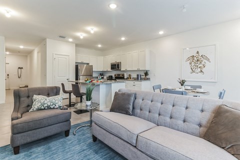 a living room with a couch and a chair and a kitchen